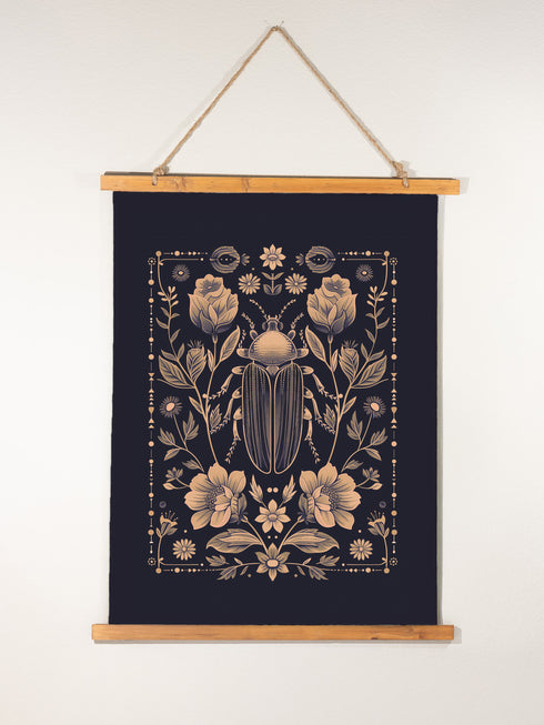 A symmetrical wall tapestry featuring a large scarab beetle in antique bronze tones surrounded by detailed flowers and botanical elements on a black background, mounted on wooden dowels with twine.